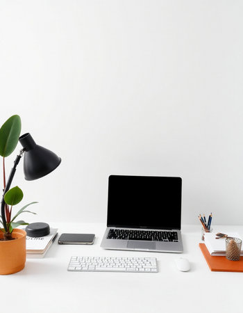 Minimal workspace with blank screen laptop computer, coffee cup and office supplies on white desk.