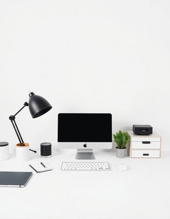 Workplace with computer, supplies and coffee cup on white table.