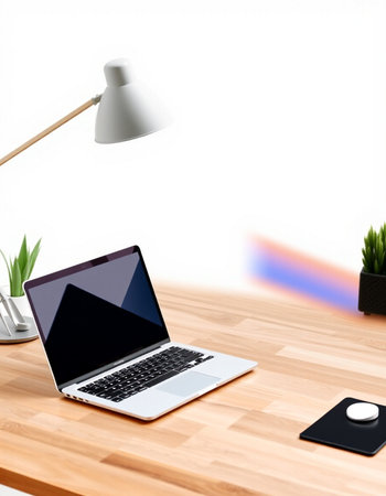 Laptop on a wooden table with a lamp and a potted plant