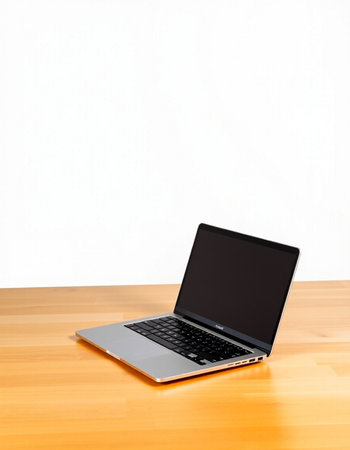 Laptop on a wooden table with a white wall in the background