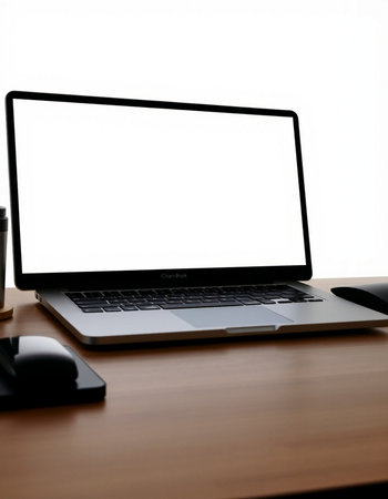 Laptop computer with blank screen on wooden table with white background.