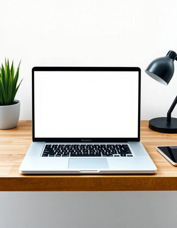 Laptop with blank screen on wooden table and white wall background.