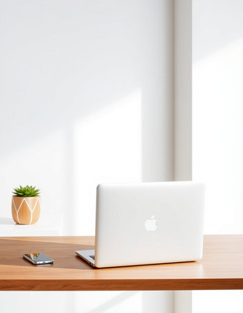 Laptop on wooden desk in modern office with white wall and sunlight