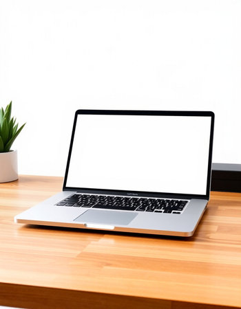 Laptop with blank screen on wood table and white wall background.