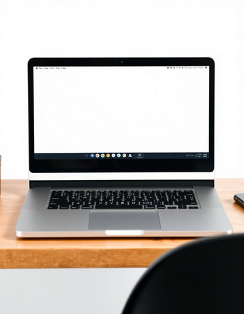 Laptop with blank screen on wooden table and white wall background.