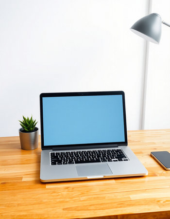 Laptop with blank screen on wood table and lamp on white wall background