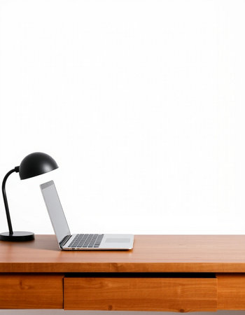 Laptop on a wooden table with a black lamp on a white background