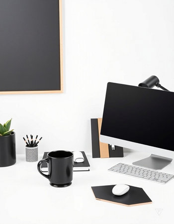 Modern workspace with computer, coffee cup, supplies and copy space on white wall.