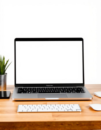 Laptop with blank screen on wooden table and white wall background.