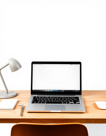 Laptop with blank screen on wooden table and white wall background.