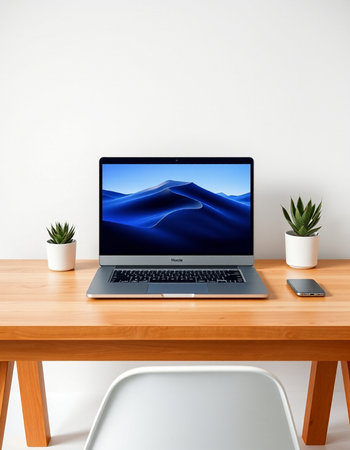 Laptop on a wooden table with a white wall in the background