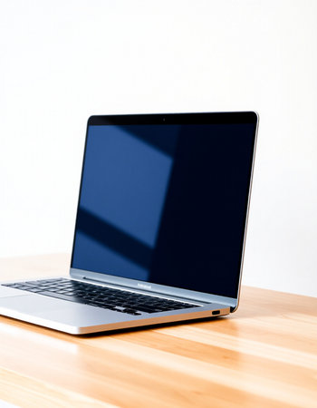 Laptop on a wooden table with a white wall in the background