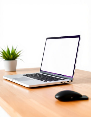 Laptop with blank screen on wooden table and white wall background.