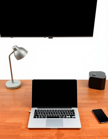 Laptop and smart phone on wooden table with white wall in background