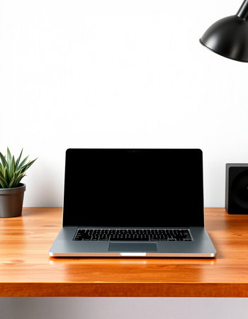 Laptop computer with blank screen on wooden table and white wall background