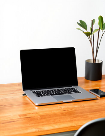 Laptop computer with blank screen on wooden table and white wall background