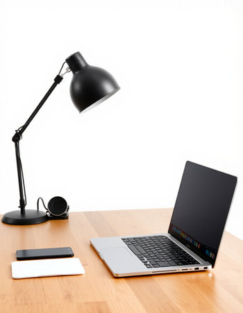 Laptop computer and lamp on a wooden desk with white wall background