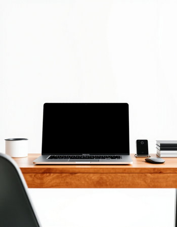 Laptop with blank screen and coffee cup on wooden table in office