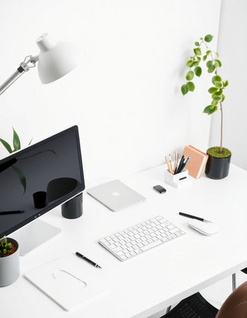 Modern workplace with computer, stationery and plants on white wall background