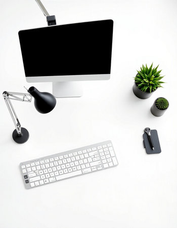 White office desk with computer, keyboard, mouse, lamp and plantの写真素材