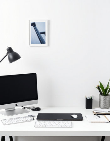 Modern workplace with computer, lamp and other items on white wall background