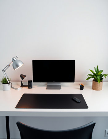 Workplace with computer, keyboard, mouse, lamp and plant.