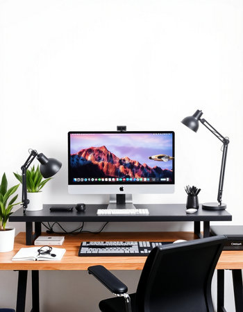 Modern workplace with computer on wooden table in front of white wall.