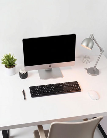 workplace with computer, keyboard, lamp and plant on the table