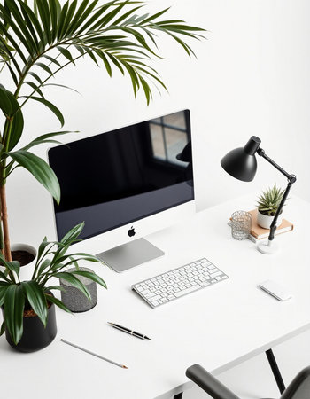 Workplace with computer, keyboard, lamp and plants on white table