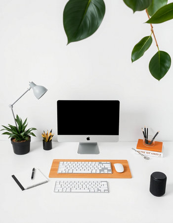 Modern workspace with computer, stationery and plants on white background.