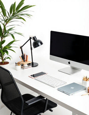 Minimalistic workplace with computer, stationery and plant on white table
