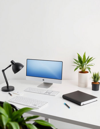 workplace with computer, keyboard, lamp and plant on white table