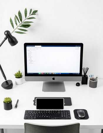 Workplace with computer, mobile phone, keyboard, mouse and plant