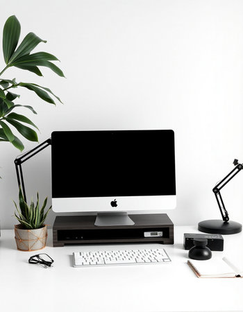 Modern workspace with computer, stationery and plant on white background.