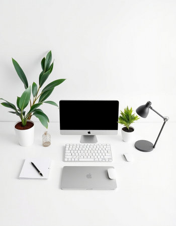 Minimal workspace with computer, keyboard, notepad, lamp and plant on white backgroundの写真素材