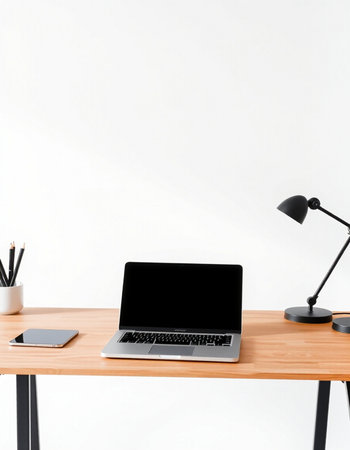 Laptop with blank screen on wooden desk and lamp on white wall background