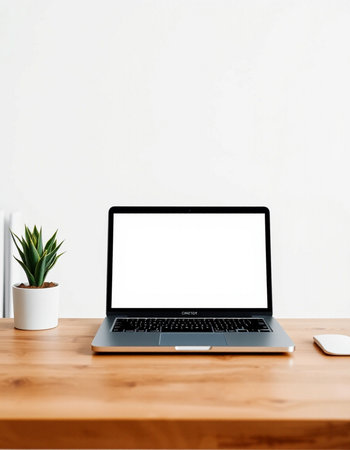 Laptop with blank screen on wooden table and white wall background.