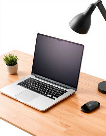 Laptop on a wooden desk with a black lamp and a plant