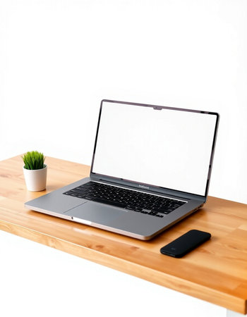 Laptop with blank screen on wooden table and white wall background.