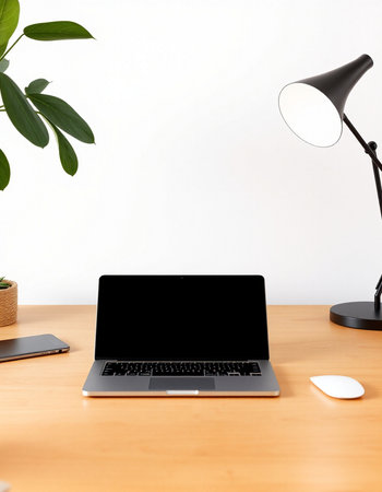 Laptop with blank screen on wooden desk with lamp and computer mouse