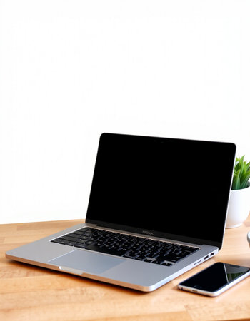 Laptop with blank screen on wood table and white wall background.