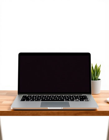 Laptop with blank screen on wooden table against white wall background.