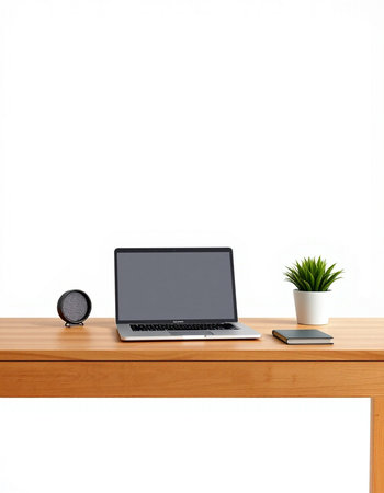 Laptop on wooden table with white wall background and green plant.