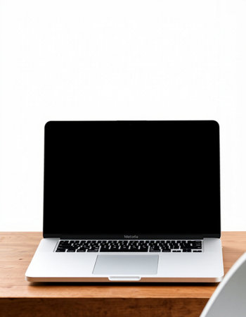 Laptop with blank screen on wooden table and white wall background.