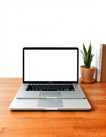 Laptop with blank screen on wooden table and white wall background.