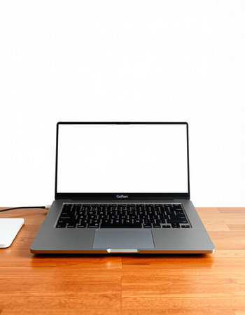 Laptop with blank screen on a wooden table and white wall background