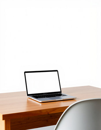Laptop with blank screen on wood table and white wall background.