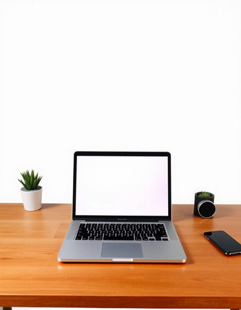 Laptop with blank screen on wooden table and white wall background.
