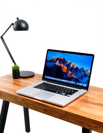 Laptop on a wooden table with a black lamp on a white background