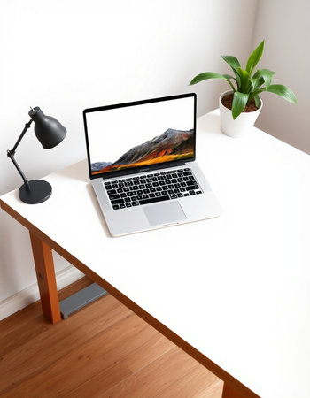 Laptop on a white desk with a lamp and a potted plant